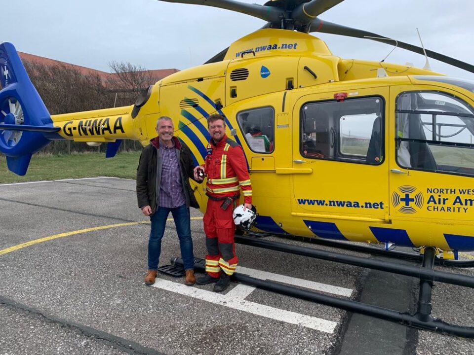 Two people in front of a yellow helicopter