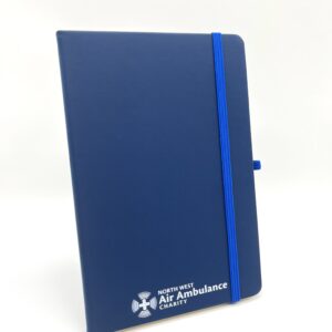 A5 size ,lined notebook with elastic page finder and pen holder. Blue cover with white North West Air Ambulance logo.