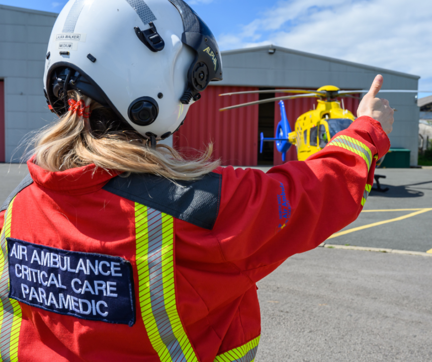 Paramedic in red suit signalling to the pilot in the helicopter