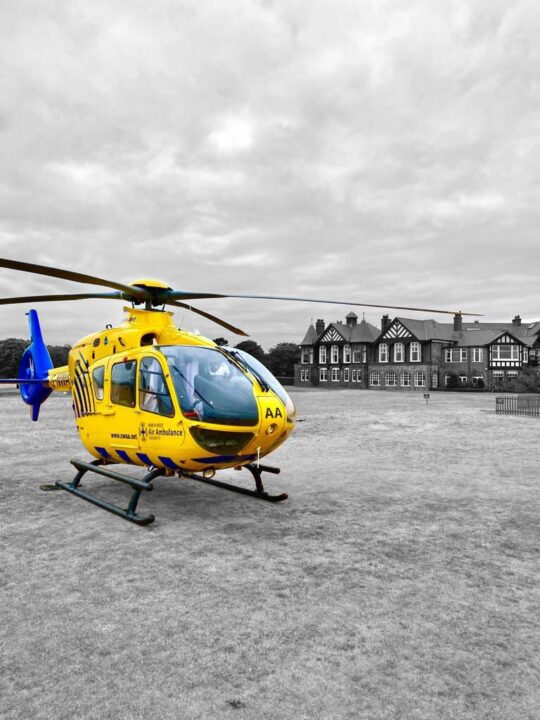 Black and white photos of Royal Lytham golf course with NWAA's helicopter yellow and blue helicopter in colour at the front of the photo