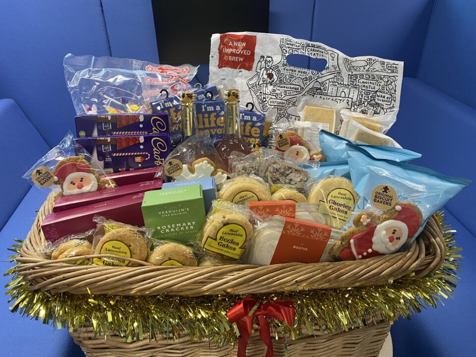 Christmas hamper sat on a table filled with foodie treats like mince pies, gingerbread and Eccles cakes. 