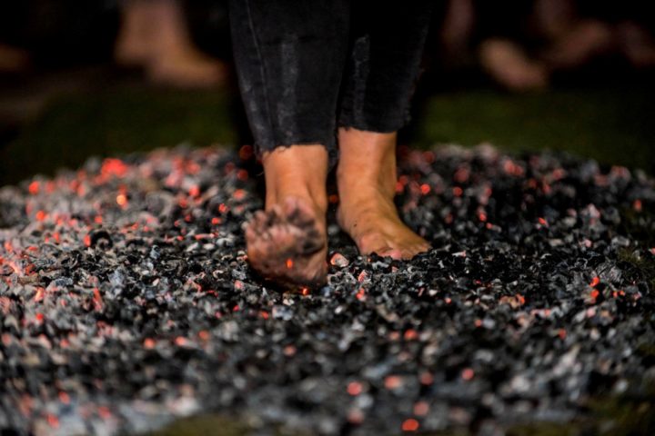 Picture of a person walking across hot coals, bear footed