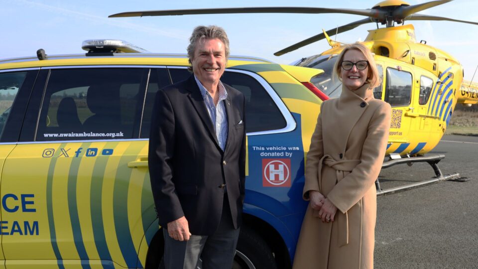 NWAA CEO Heather Arrowsmith and Robert Bertram,  Chief Executive of the HELP Appeal stood in front of the yellow critical care car and helicopter 