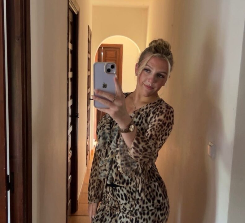 Star stood posing for a photo in front of a mirror while wearing a summery dress