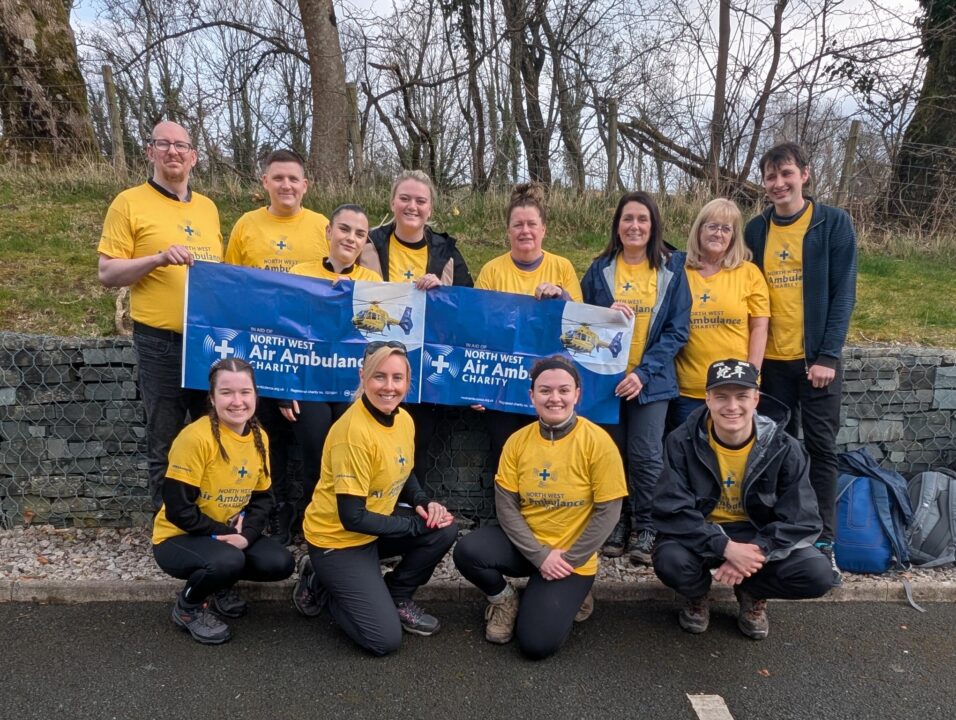 Group of fundraisers from M&S, they are wearing branded NWAA T shirts and holding up a branded banner