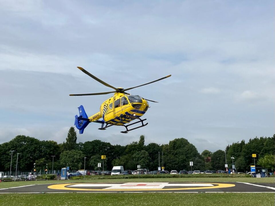 Yellow and blue helicopter taking off from a hospital helipad