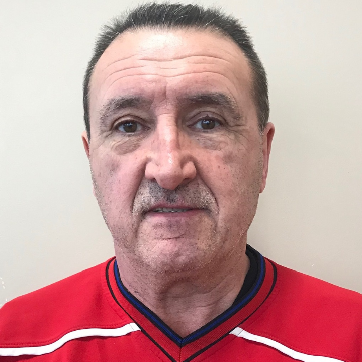 Headshot of a middle-aged man with short dark hair and light skin, looking directly at the camera against a plain background.